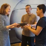 Maria Larsson på Uminova Innovation överlämnar datorer till Malek Suhail och Saleh Suhail på Junis i Umeå